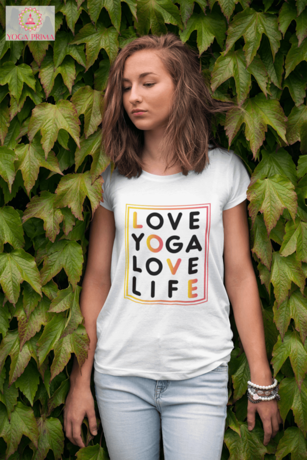 Junge Frau mit unserem Love Yoga Love Life Shirt in weiß vor einer Hecke